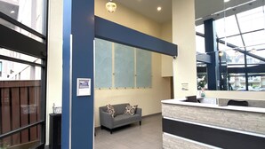 A reception area with a modern design, featuring a grey sofa, a reception desk, and a large window providing natural light. - Luxury Oceanfront Condo  (Long Beach)