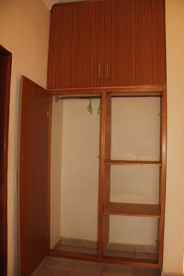 A room with a wooden wardrobe, a door, and a tiled floor.