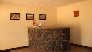 Una zona de recepción con mostrador de piedra, cuadros en la pared y una lámpara en el techo.
