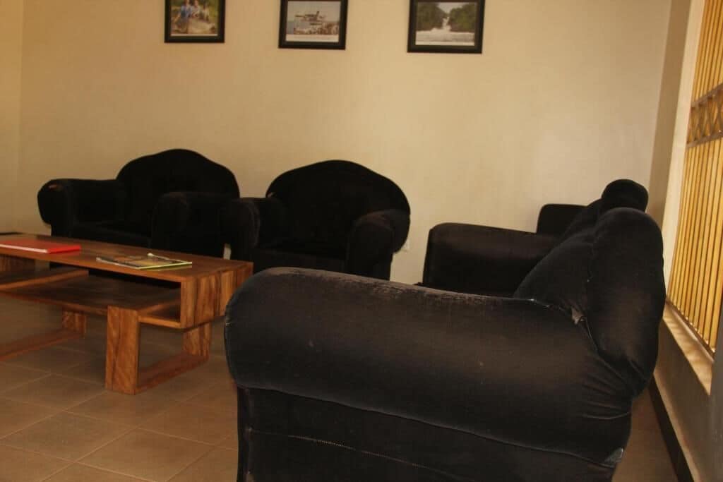 A room with three black armchairs, a wooden coffee table, and a framed picture on the wall.