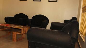 A room with three black armchairs, a wooden coffee table, and a framed picture on the wall.