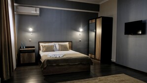 Une chambre d’hôtel moderne dotée d’un grand lit, de tables de chevet, d’un téléviseur à écran plat et d’un système de climatisation.
