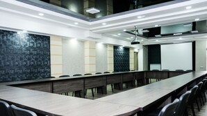 Une salle de conférence équipée d’une longue table, de chaises et d’un écran de projection.