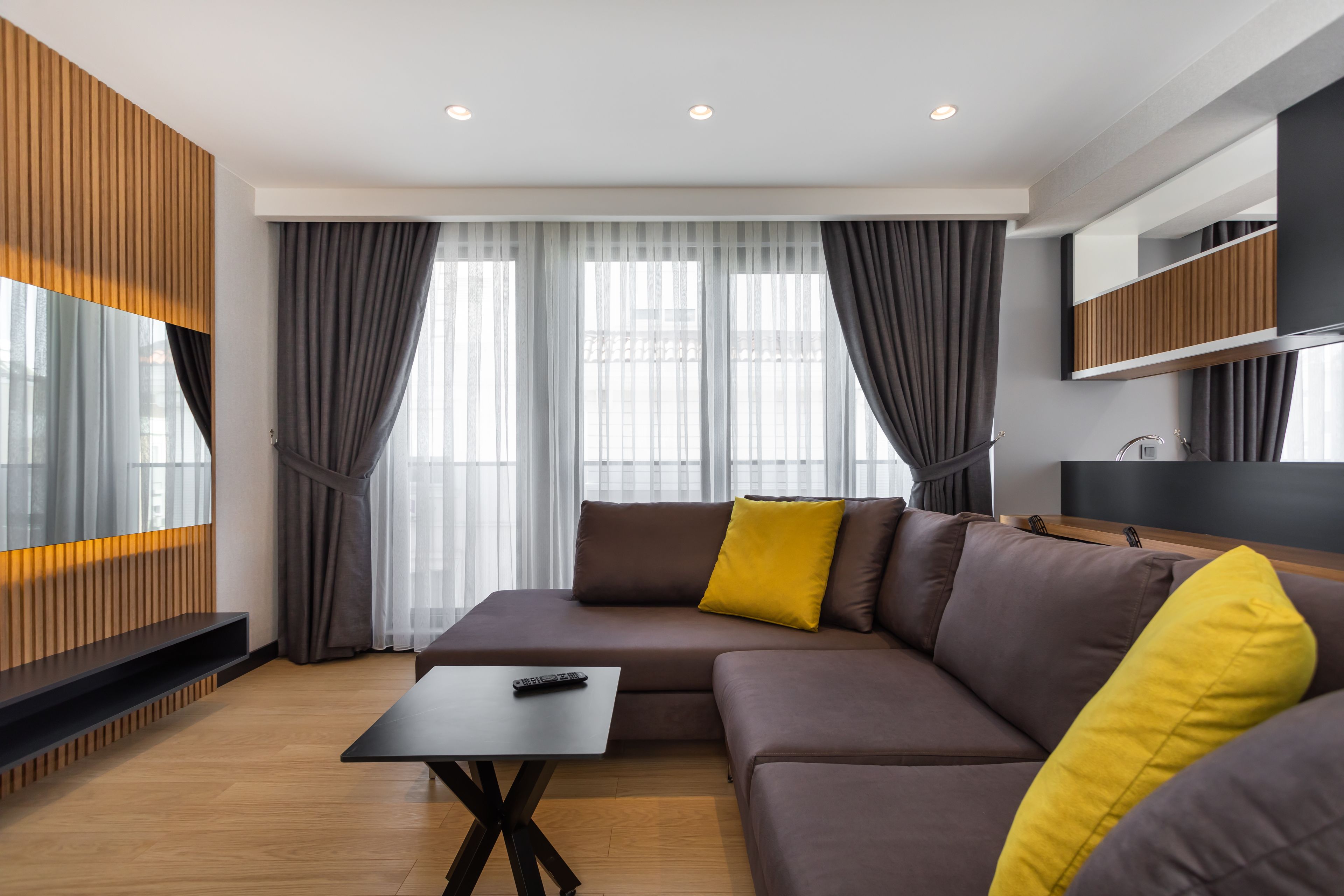 A modern living room with a sectional sofa, a coffee table, and a TV mounted on the wall.