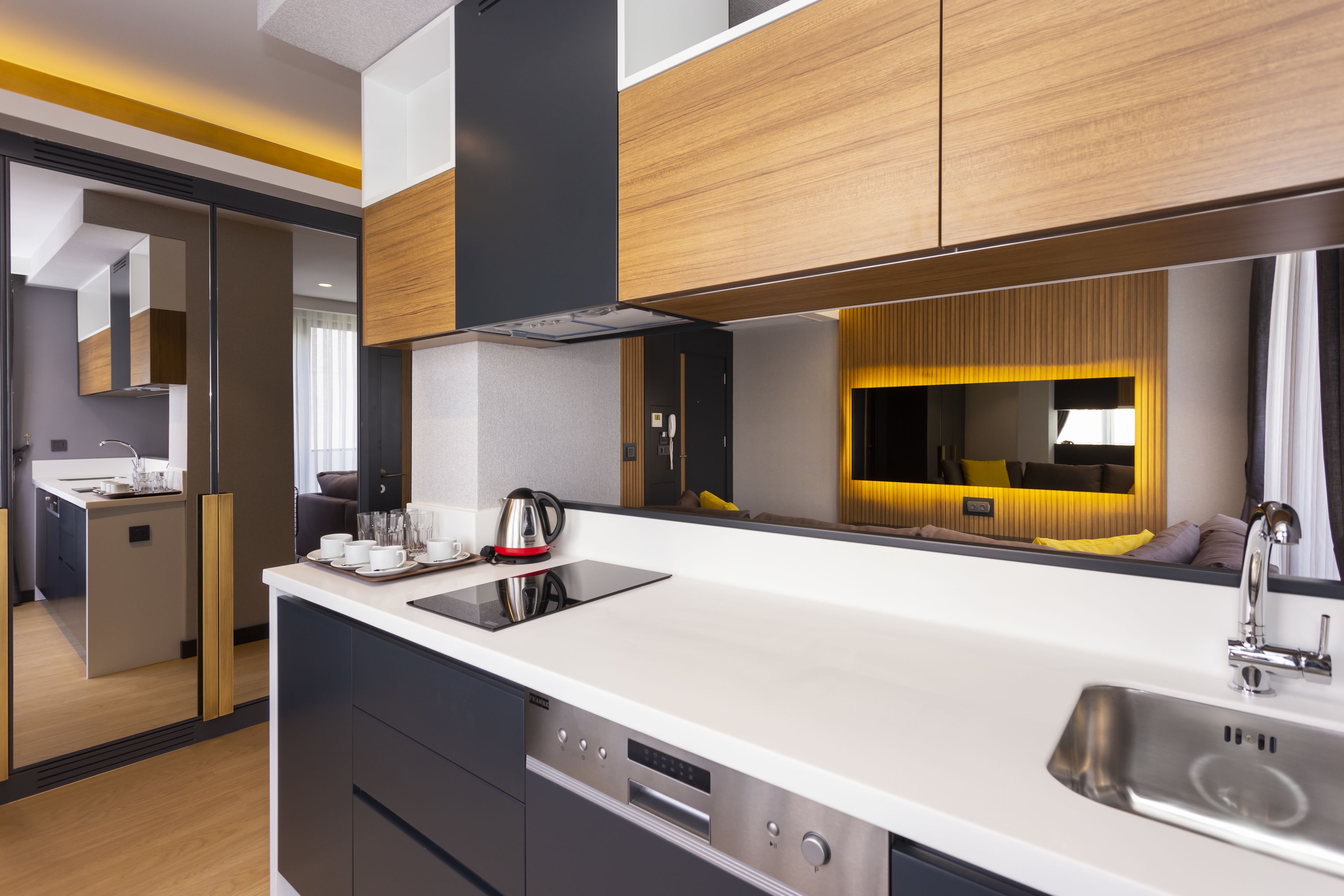 A modern kitchen with a central island, built-in oven, and stainless steel sink.