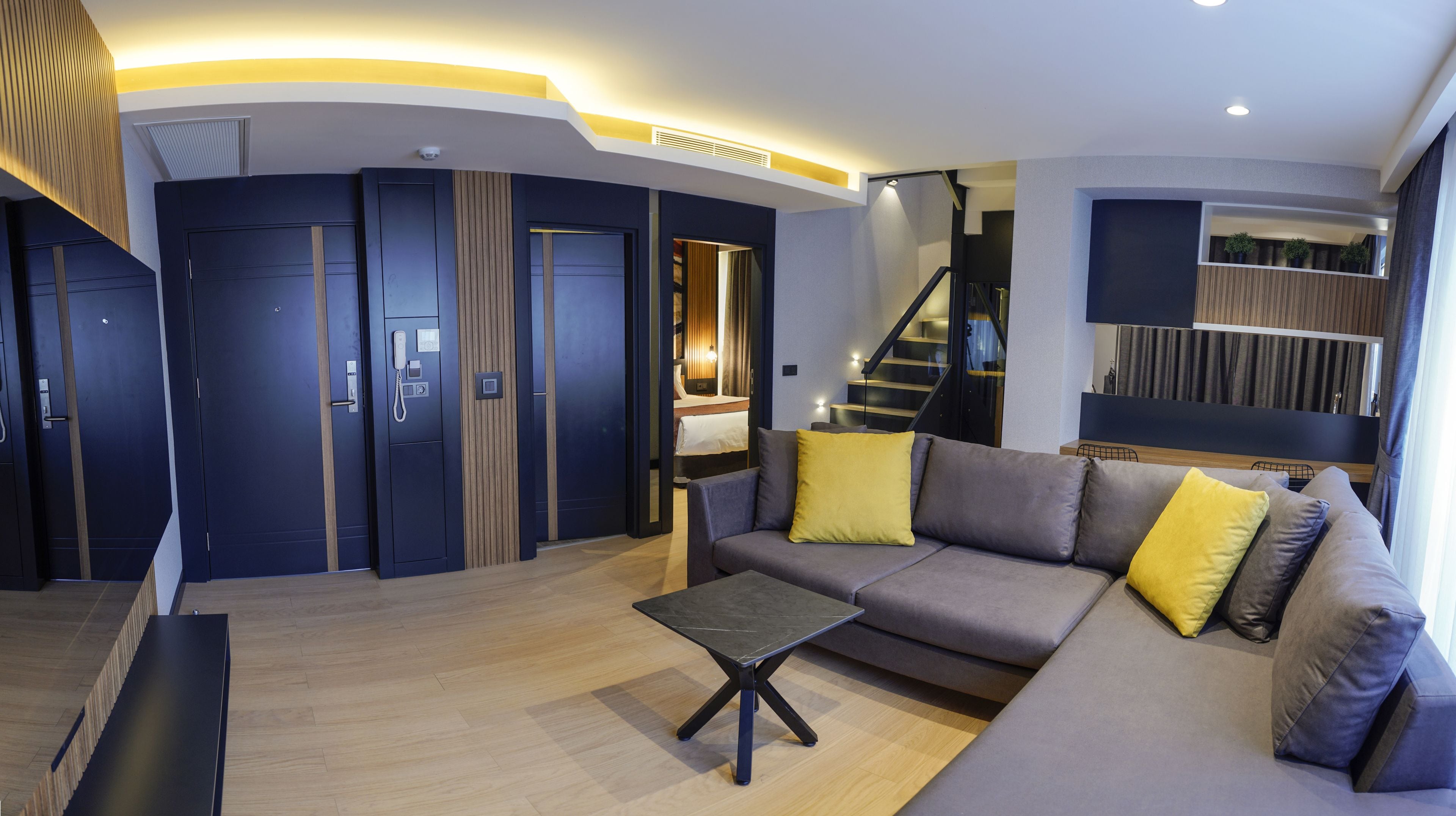 Een moderne woonkamer met een bank, een salontafel en een trap naar een hoger niveau.
