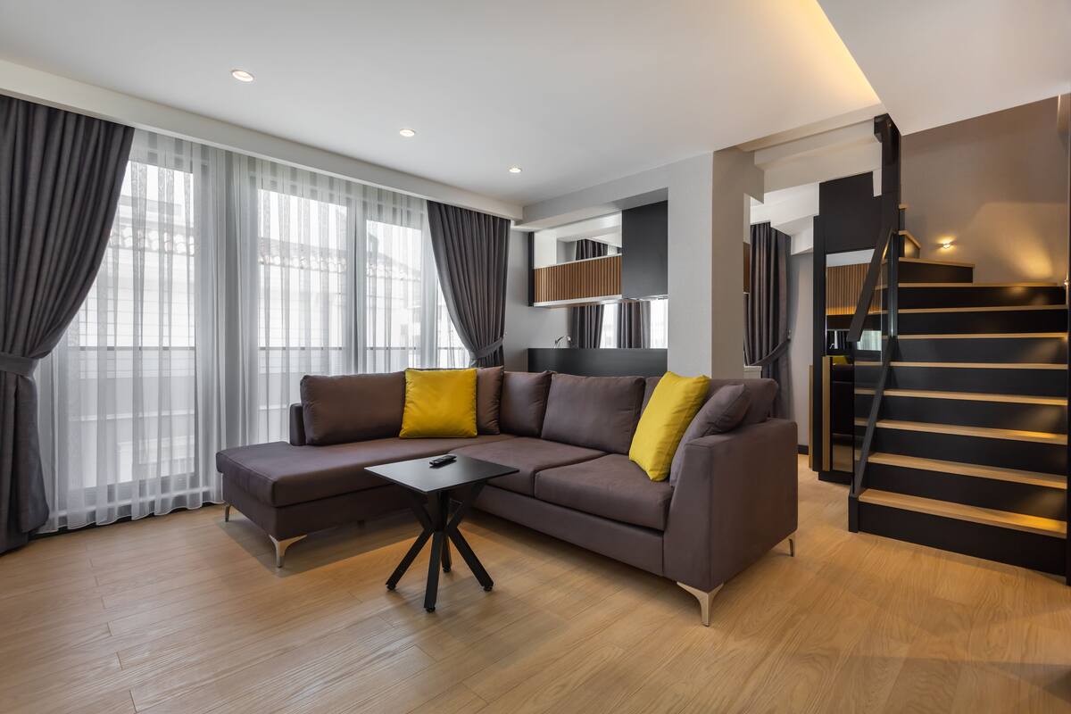 A modern living room with a sectional sofa, a coffee table, and a staircase.