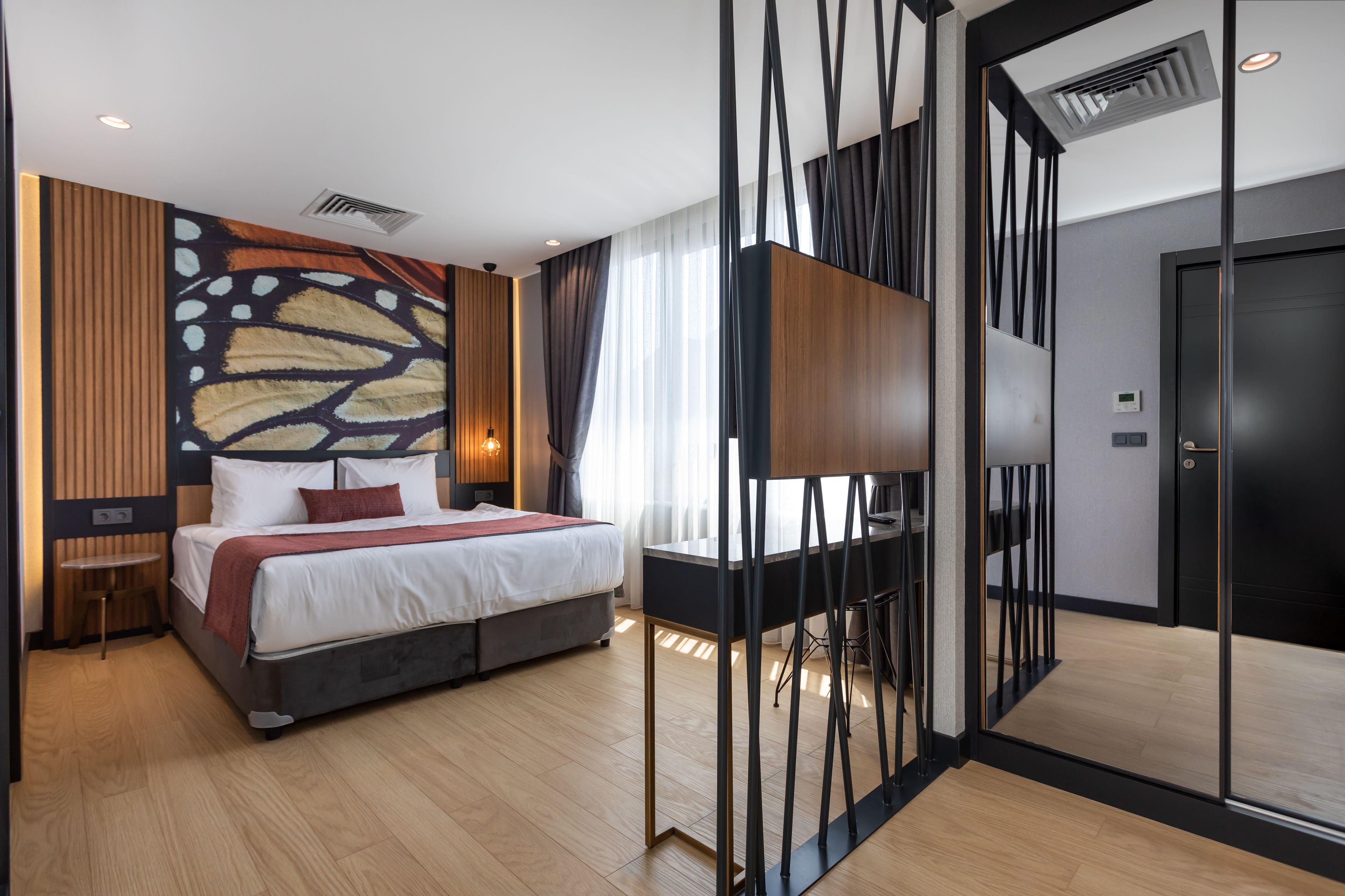 Ein modernes Hotelzimmer mit einem großen Bett, einem Schreibtisch und einem Fernseher.