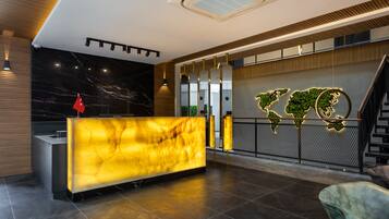 A modern reception area with a marble reception desk, a world map mural, and a staircase.