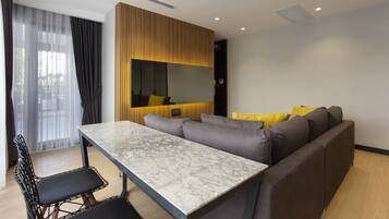A modern living room with a marble table, grey sofa, and yellow cushions.