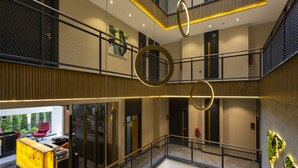 A multi-level hotel lobby with a reception desk, a staircase, and a glass railing. - Nox Suite (Antalya)
