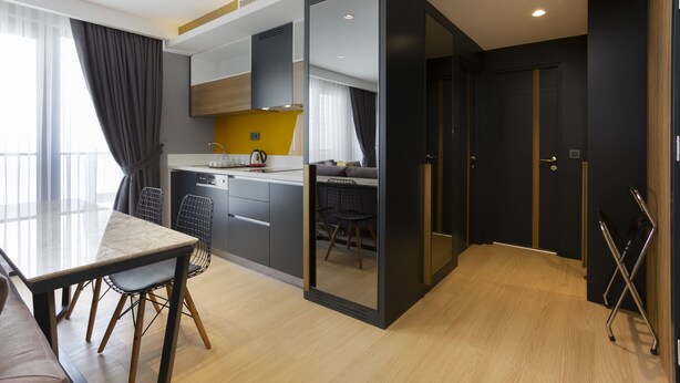 A modern kitchen with a dining area, a sofa, and a view of the city. - Nox Suite (Antalya)