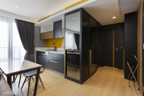 A modern kitchen with a dining area, a sofa, and a view of the city. - Nox Suite (Antalya)