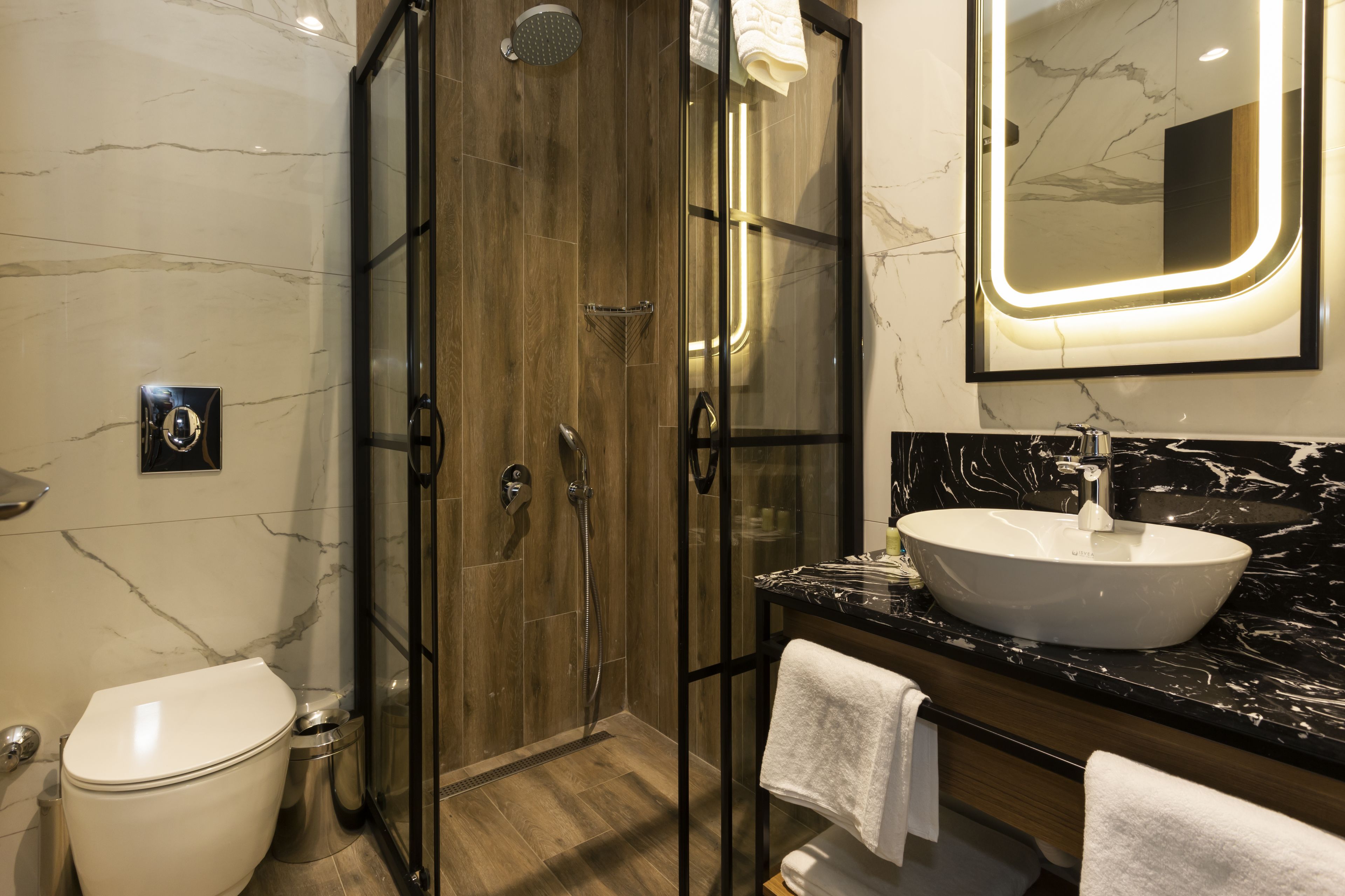 A modern bathroom with a glass-enclosed shower, a white sink, and marble walls.