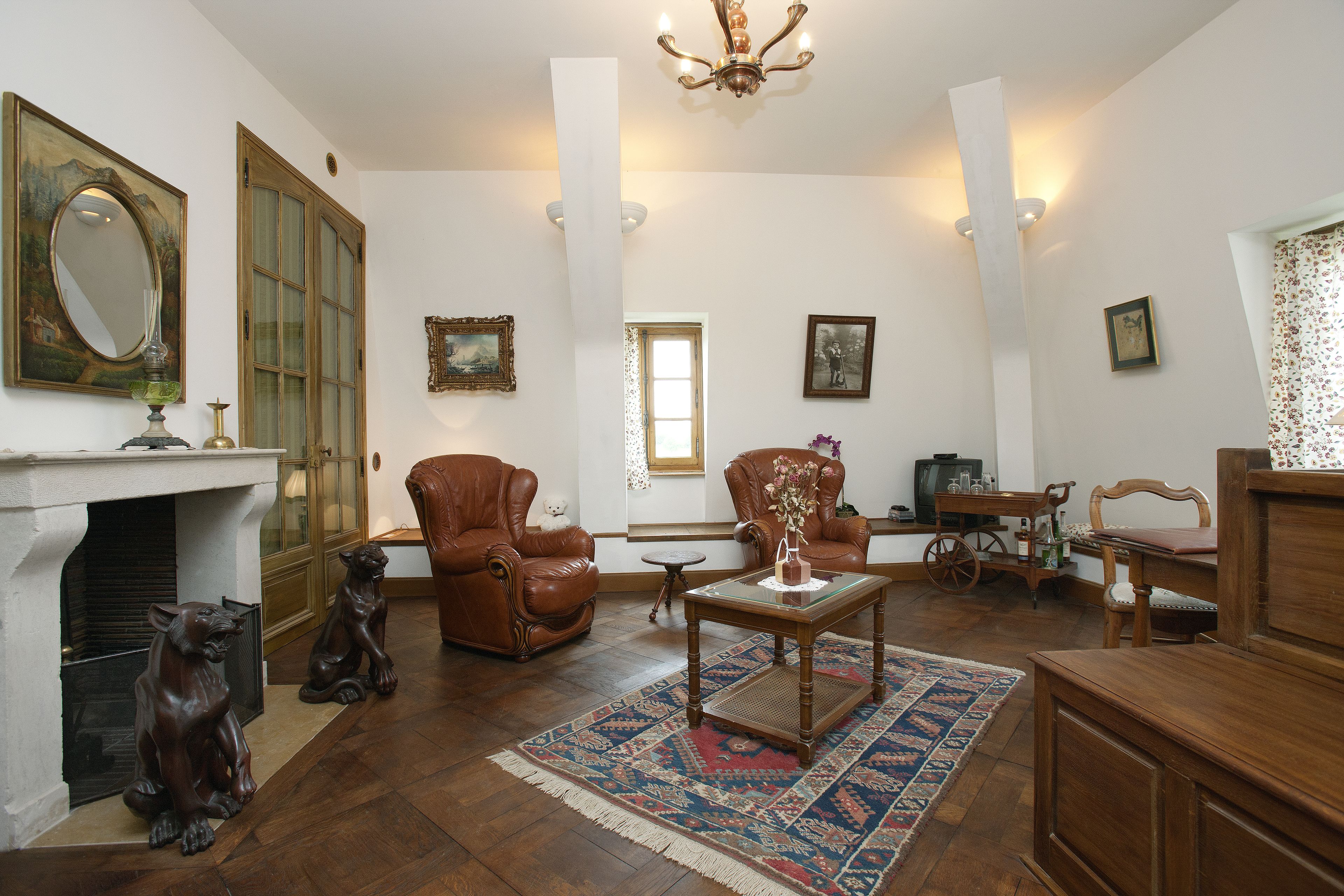 Un salon spacieux avec une cheminée, des fauteuils en cuir, une table basse en bois et un grand miroir.