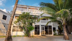 A two-story building with a white facade, large windows, and a balcony with a lattice design. - Island getaway with amazing views (San Pedro)
