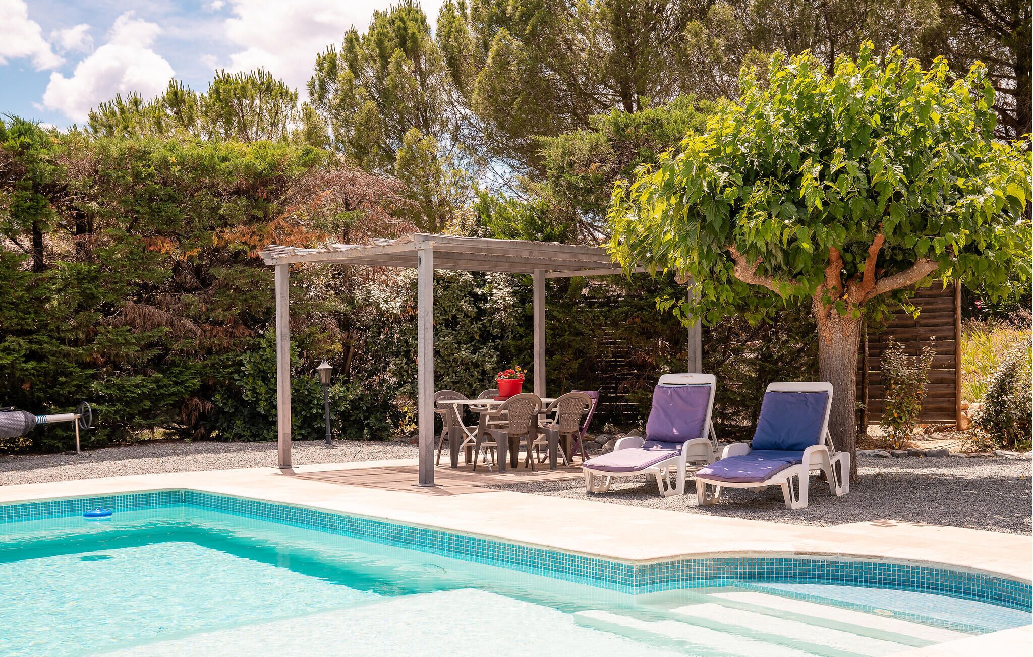 Piscina com espreguiçadeiras e pérgola.