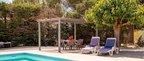 Piscina com espreguiçadeiras e pérgola.