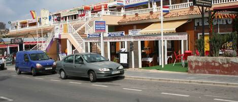Vista de la calle con varios restaurantes y una pizzería.