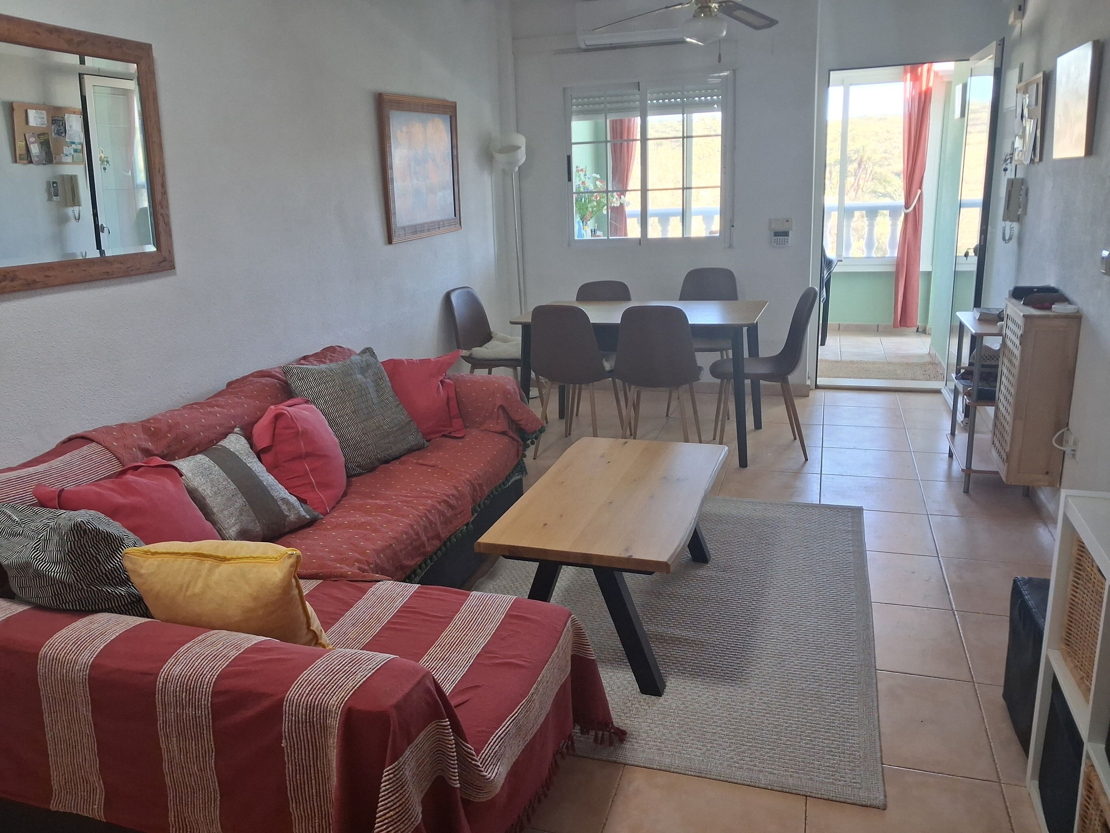 Una sala de estar con un sofá, una mesa de madera y un comedor con sillas.