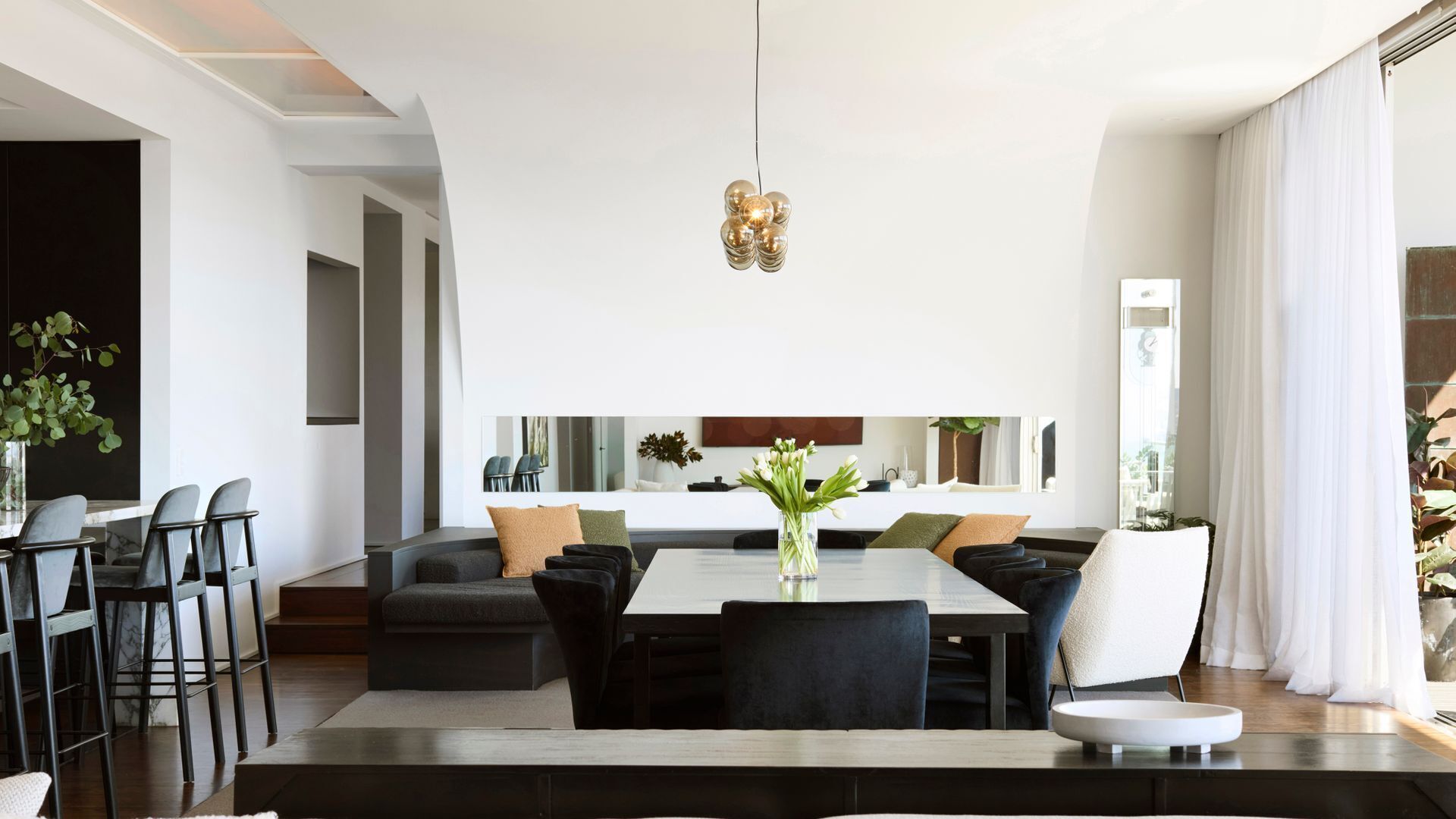 Una sala moderna con una gran mesa de comedor, sofás y una cocina al fondo.