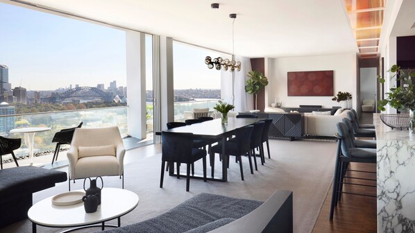 A modern living room with a dining area, large windows offering a city view, and a kitchen with a large island. - Sky Loft by Contemporary Hotels (DARLINGHURST)