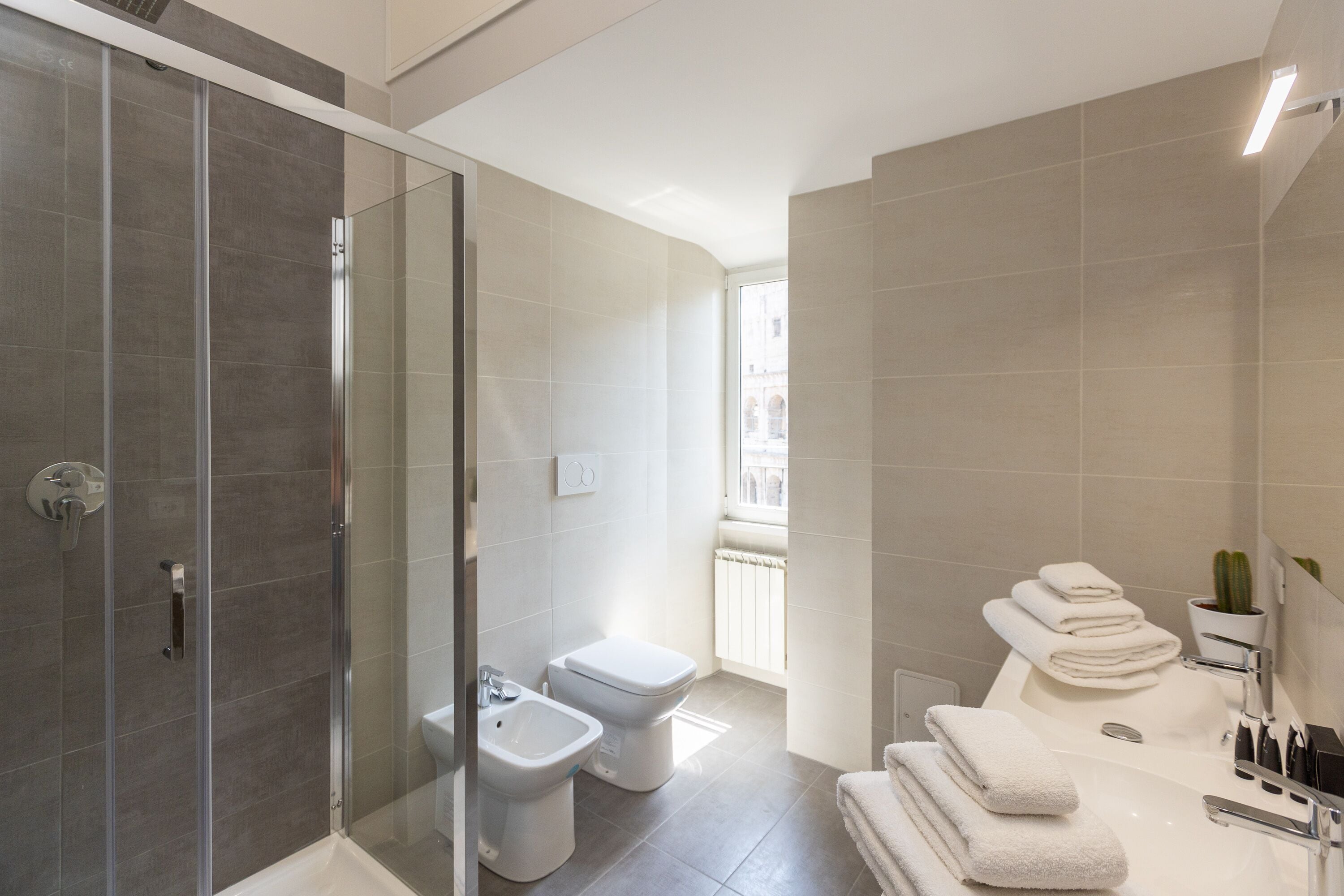 Une salle de bain moderne avec une douche à parois de verre, des toilettes, un bidet et une baignoire, ainsi que des serviettes.