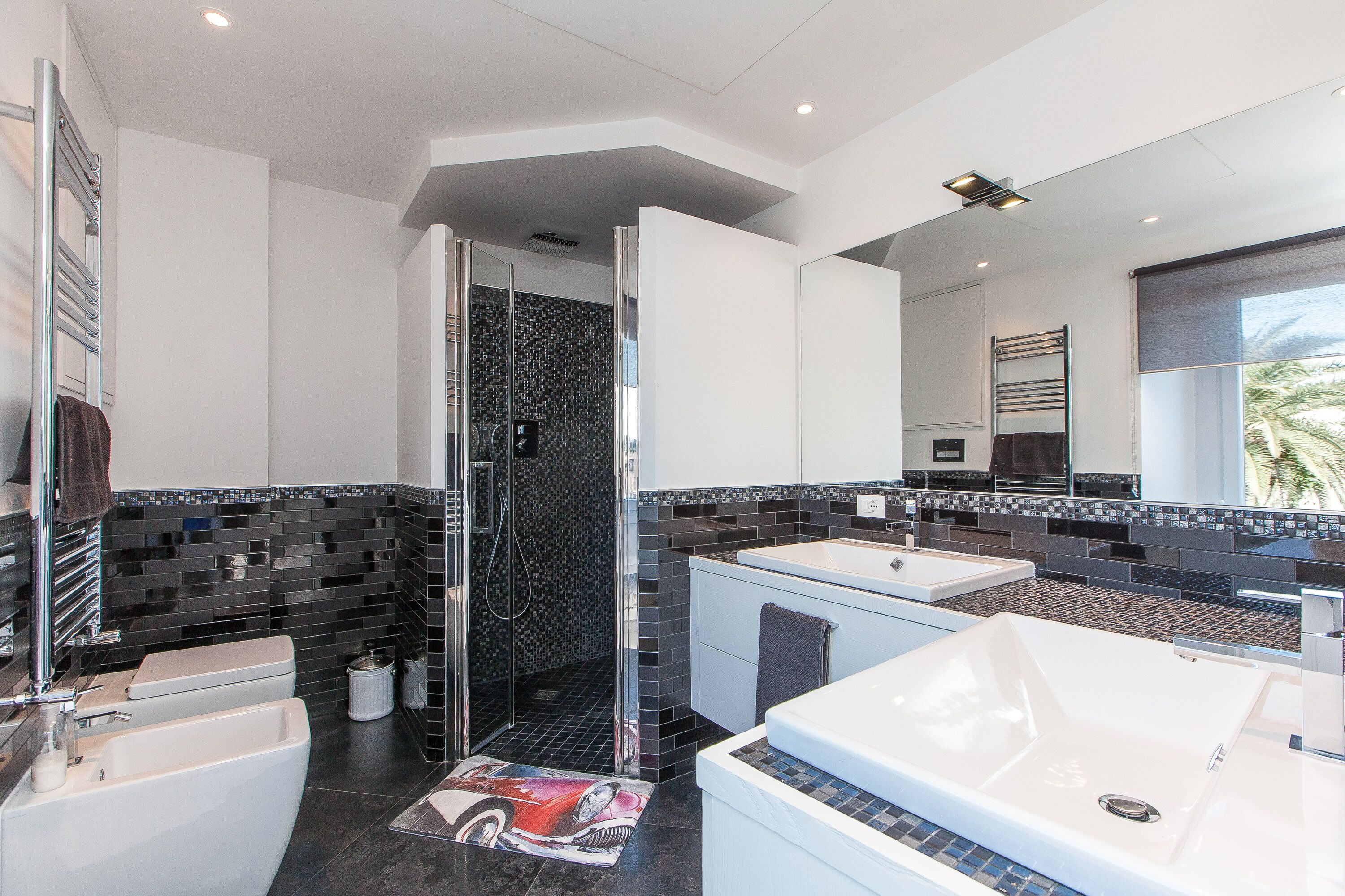 Un baño moderno con cabina de ducha de vidrio, una bañera grande y un tocador con espejo.