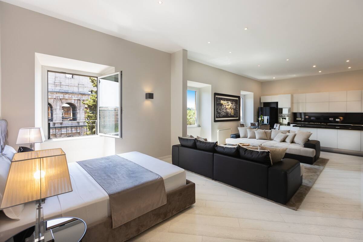 A modern living room with a sofa, a bed, and a kitchen area.