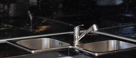 A kitchen with two stainless steel sinks and a black countertop.