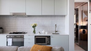 A modern kitchen with white cabinetry, a gas stove, an oven, a microwave, and a sink. - Sky Pad by Contemporary Hotels (DARLINGHURST)
