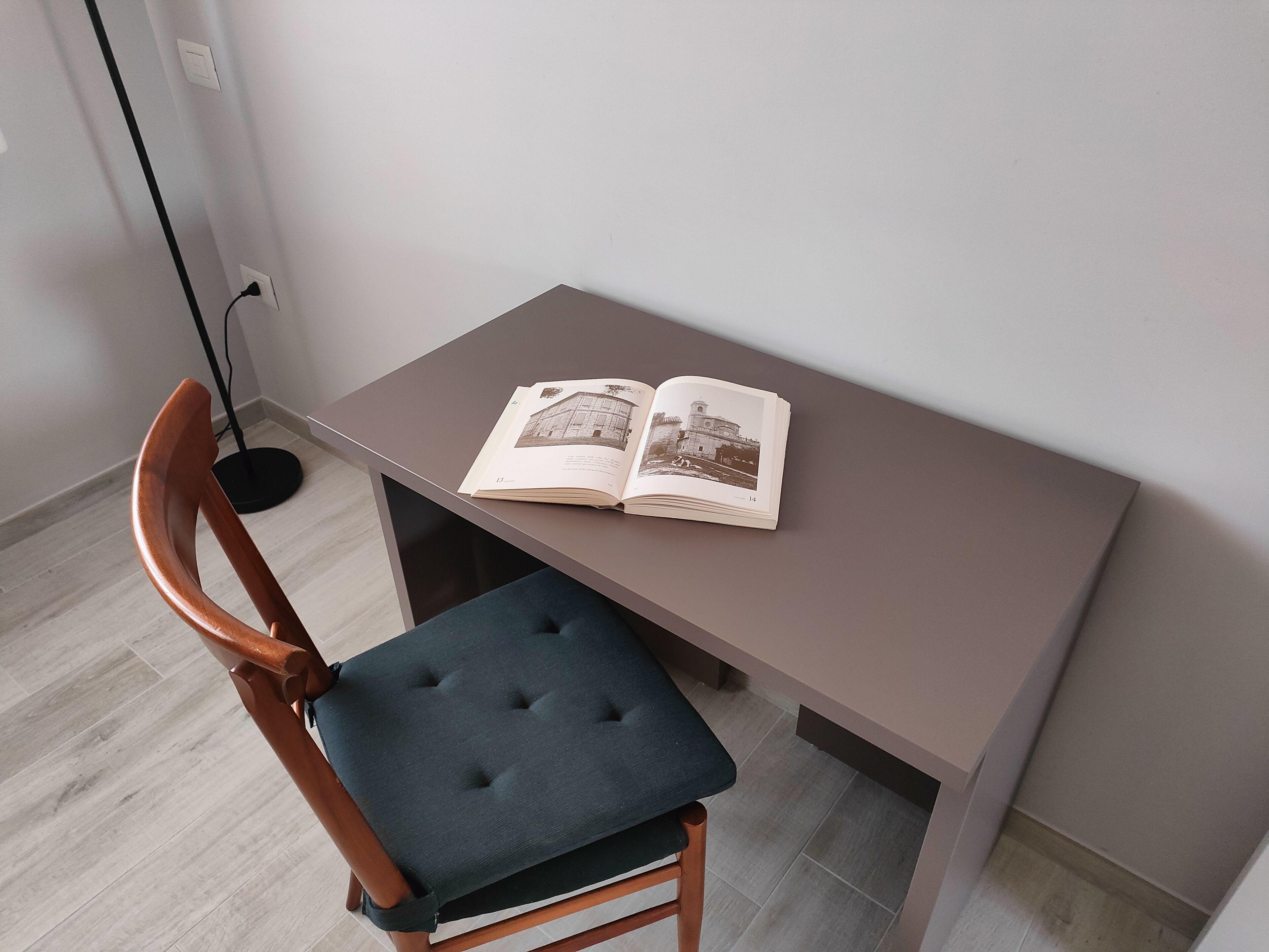 A small study area with a wooden chair and a table. An open book is placed on the table.