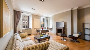 Un salon spacieux comprenant un canapé, un fauteuil et une table basse. On y trouve également une cheminée, un téléviseur et un coin repas avec des chaises et une table.
