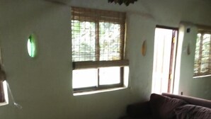 A room with a sofa, a small table, and a window with blinds.