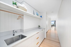 Une cuisine moderne dotée d’un évier encastré, de meubles blancs et d’un plancher en bois.