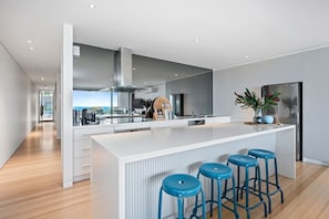 Une cuisine moderne dotée d’un grand îlot central, de tabourets de bar et offrant une vue sur l’extérieur.
