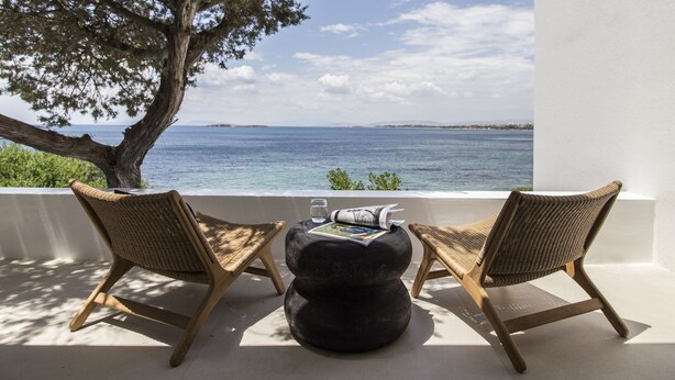 A terrace with two wicker chairs and a round table, overlooking a body of water and a distant coastline. - The Margi Villa (Vari-Voula-Vouliagmeni)