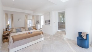 Une chambre spacieuse avec un grand lit, une table de chevet, une chaise et un escalier menant à un  étage supérieur.