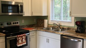 A kitchen with white cabinets, a stainless steel microwave, stove, and dishwasher. - Blue Ridge Cottage Walking Distance to Downtown Waynesville (Waynesville)