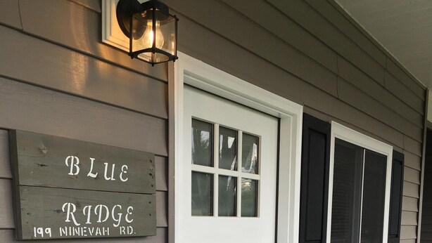 A house with a white front door, a sign reading "Blue Ridge 199 Nineveh Rd.", and a porch with a black railing. - Blue Ridge Cottage Walking Distance to Downtown Waynesville (Waynesville)