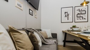 A modern living room with a grey sofa, a wooden dining table, and framed artwork on the wall. - APT Prague Ch. Bridge by Michal&Friends (Prague)
