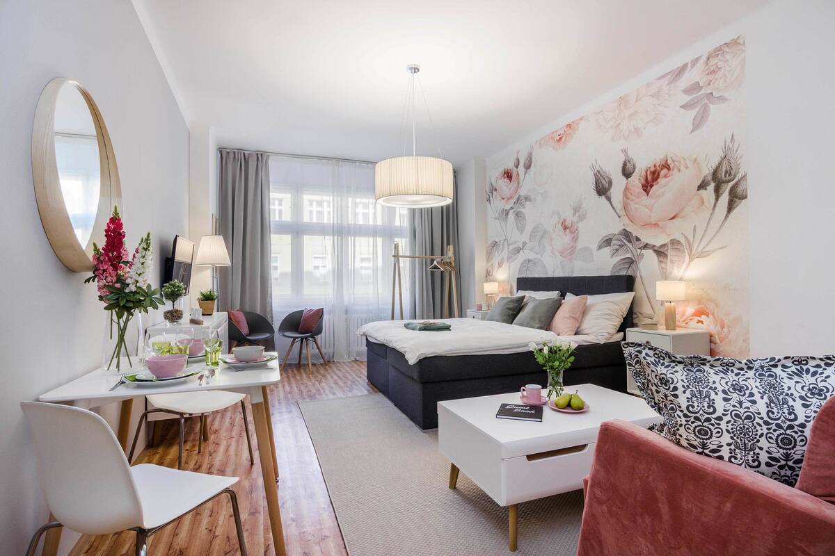 A modern bedroom with a bed, bedside table, and a large floral wall mural.