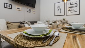 A dining area with a wooden table set for four, including plates, bowls, and cutlery. - APT Prague Ch. Bridge by Michal&Friends (Prague)