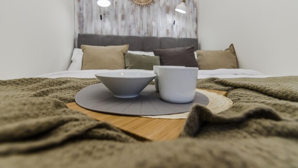 A neatly made bed with a grey and white color scheme, a wooden headboard, and a decorative wall piece above it. - APT Prague Ch. Bridge by Michal&Friends (Prague)