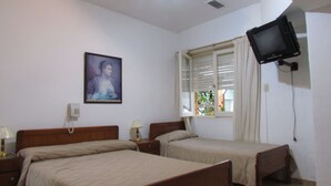 A bedroom with two beds, a television mounted on the wall, a window with blinds, and a painting on the wall. - Hotel San Carlos (Buenos Aires)