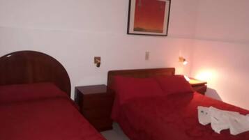 Una habitación con dos camas individuales, cada una con cabecero de madera y ropa de cama roja. Hay un cuadro enmarcado en la pared sobre las camas.