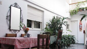 A dining area with a table set for two, surrounded by chairs, a decorative mirror, and potted plants. - Hotel San Carlos (Buenos Aires)