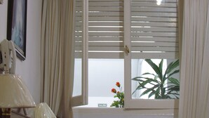 A room with a window featuring horizontal blinds, a lamp, and a potted plant on the windowsill. - Hotel San Carlos (Buenos Aires)