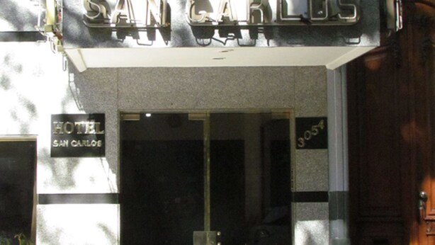 The exterior of the San Carlos Hotel with a sign above the entrance and a door number. - Hotel San Carlos (Buenos Aires)