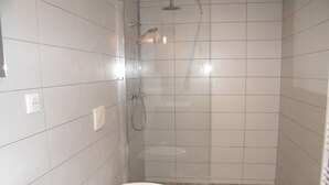 A small, tiled bathroom with a shower, toilet, and sink. - 4 The Courtyard Award Winning 4 Star Vineyard Gite (Monbadon)